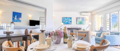 A dining area with a round table set for four, surrounded by bookshelves and a large mirror.