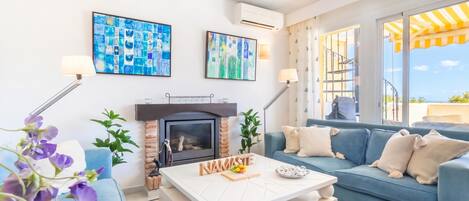 Ein modernes Wohnzimmer mit Kamin, blauem Sofa und Kunstwerken an den Wänden.