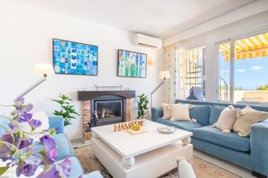 A modern living room with a fireplace, blue sofa, and artwork on the walls. - Calahonda Golf (Mijas)