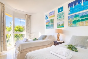 A hotel room with two beds, a large window, and artwork on the walls. - Calahonda Golf (Mijas)