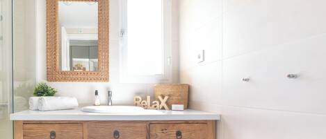 A bathroom with a wooden vanity, a large mirror, and a towel rack.