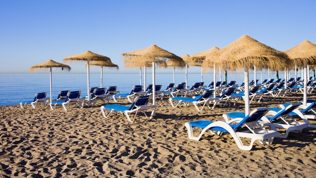 A beach with rows of sun loungers and thatched umbrellas. - Calahonda Golf (Mijas)