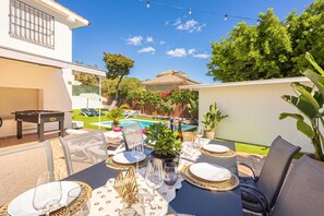 An outdoor dining area with a pool view, a foosball table, and a potted plant. - Villa Caribe Playa (Marbella)