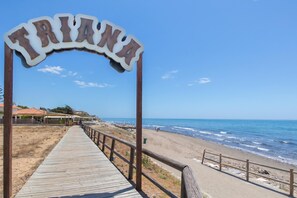 A wooden boardwalk leading to a beach with a sign reading 'TRIANA'. - Villa Caribe Playa (Marbella)