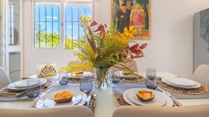 Una mesa de comedor puesta con platos, vasos y un jarrón de flores.
