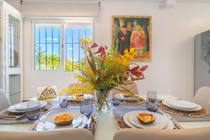 A dining table set with plates, glasses, and a vase of flowers. - Villa Caribe Playa (Marbella)