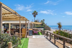 A beachside restaurant with outdoor seating, a wooden deck, and a view of the ocean. - Villa Caribe Playa (Marbella)