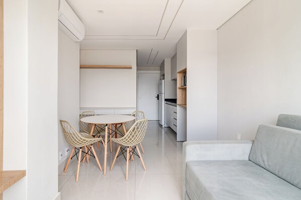 A modern, minimalist living space with a dining area, a sofa, and a kitchen in the background. - 360 Paraiso (São Paulo)