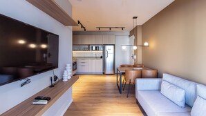 A modern living room with a flat-screen TV, a wooden console table, a sofa, and a dining area with a table and chairs. - 360 Paraiso (São Paulo)