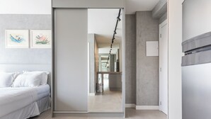 A modern bedroom with a bed, a sliding door leading to a kitchen, and artwork on the wall. - 360 Paraiso (São Paulo)