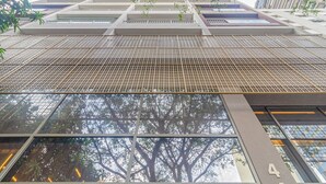 A modern building with a grid-like facade, large windows, and a tree reflection. - 360 Paraiso (São Paulo)