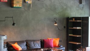 A spacious living room with a high ceiling, a leather sofa, a coffee table, and a rustic wooden chair. - 10 ponds, Nature & Architecture, 6-8p (Florennes)
