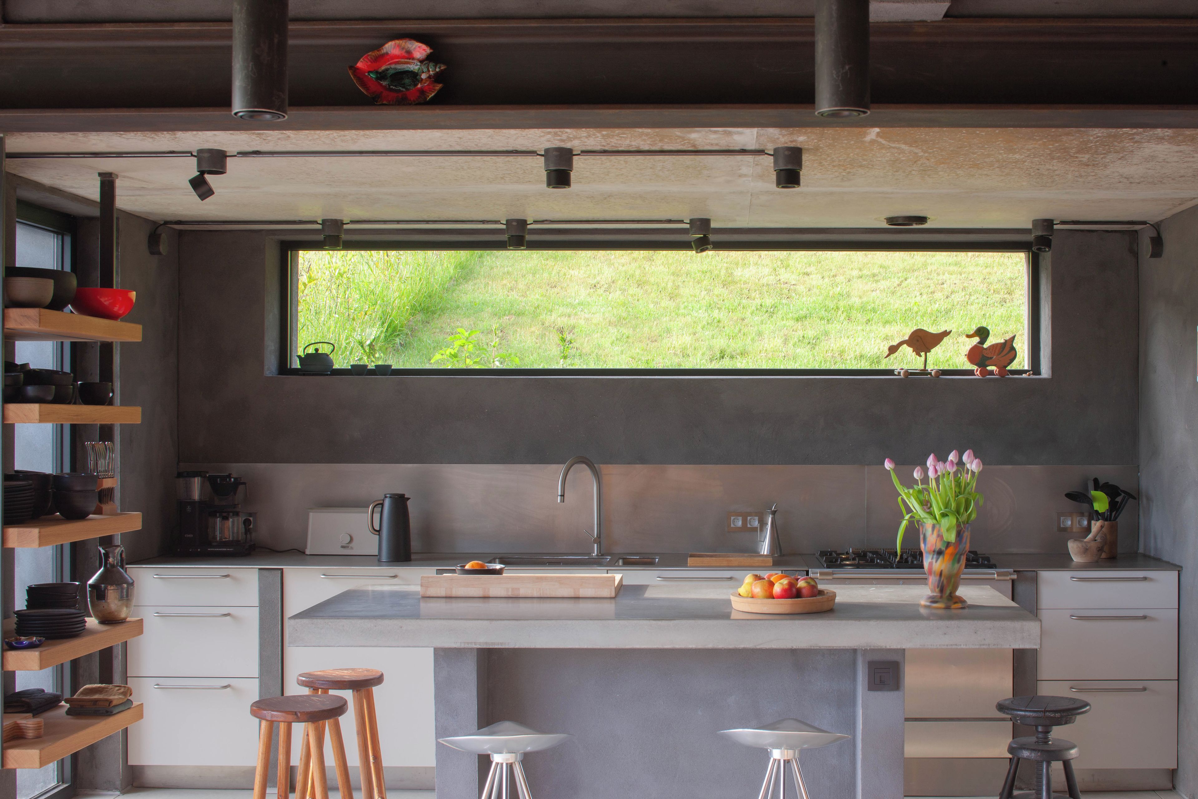 A modern kitchen with a large window, a sink, and bar stools.