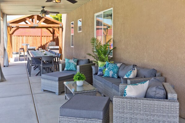 An outdoor patio with wicker furniture, a glass-top table, and a ceiling fan. - LAZY RIVER• Splash park• Pedal boats• Water slide• Theater• Arcades• Volleyball  (Coachella)