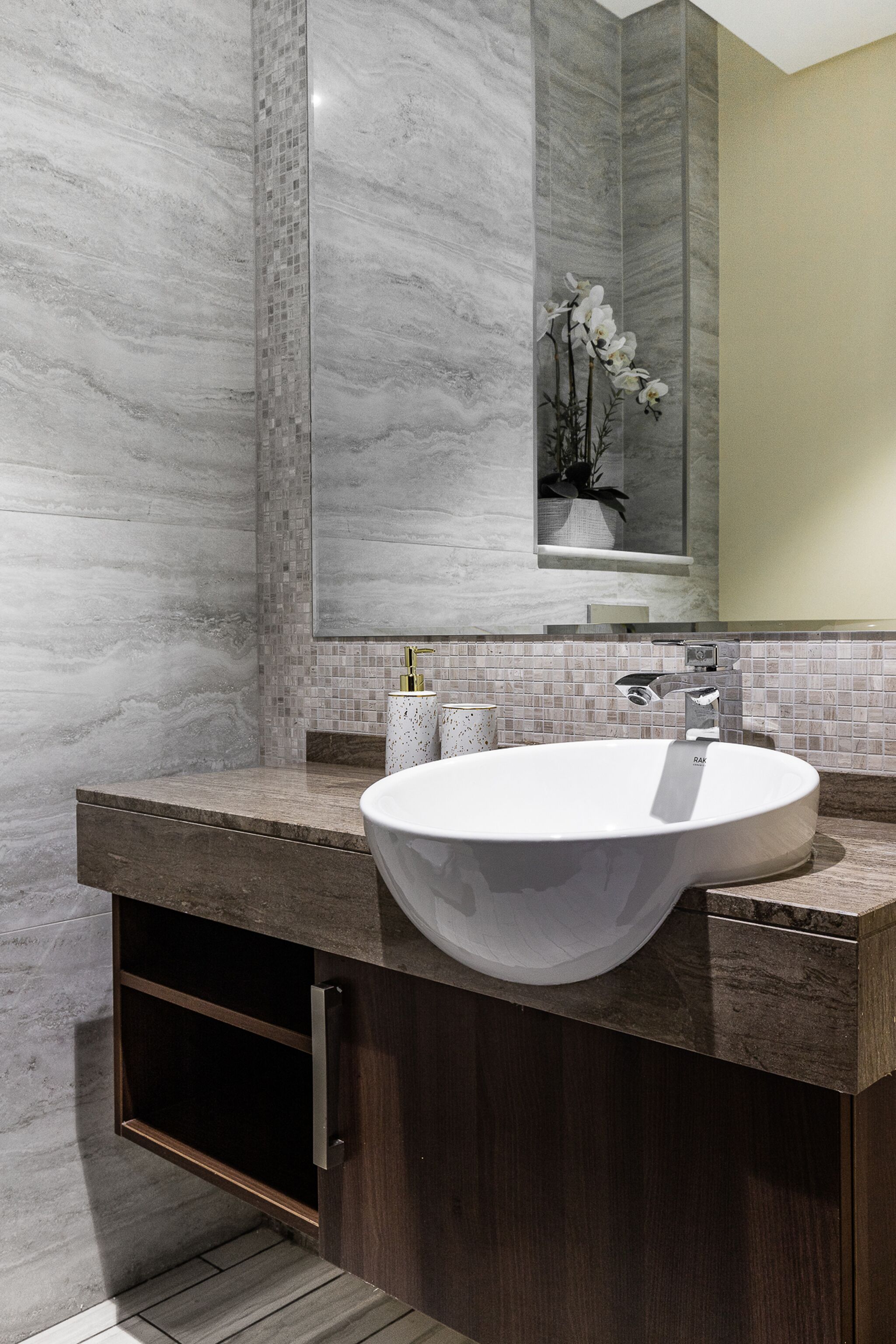 Un baño moderno con un lavamanos grande y redondo, un espejo y un salpicadero de azulejos.