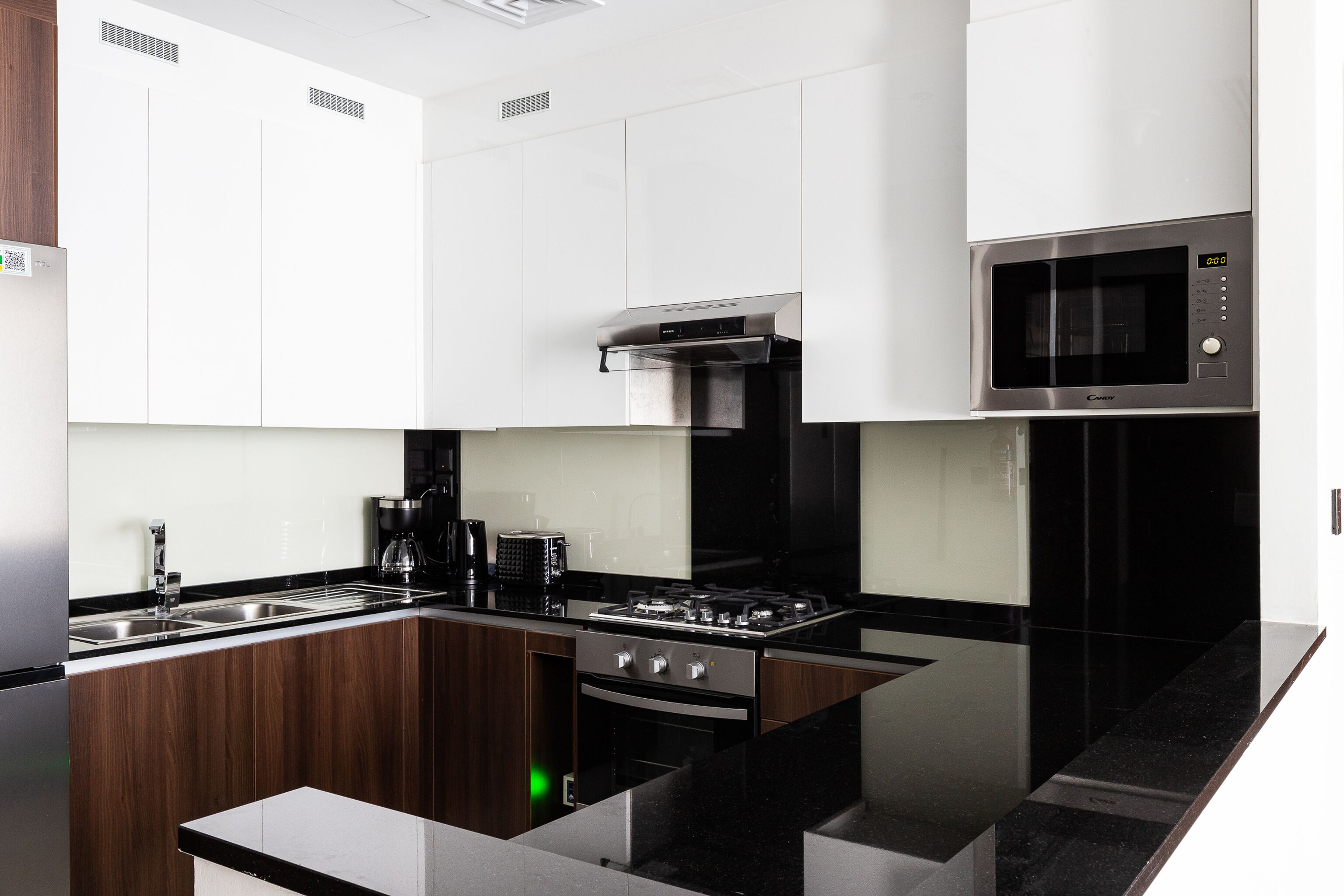 Una cocina moderna con gabinetes blancos, una estufa de acero inoxidable, un microondas y una cocina a gas.