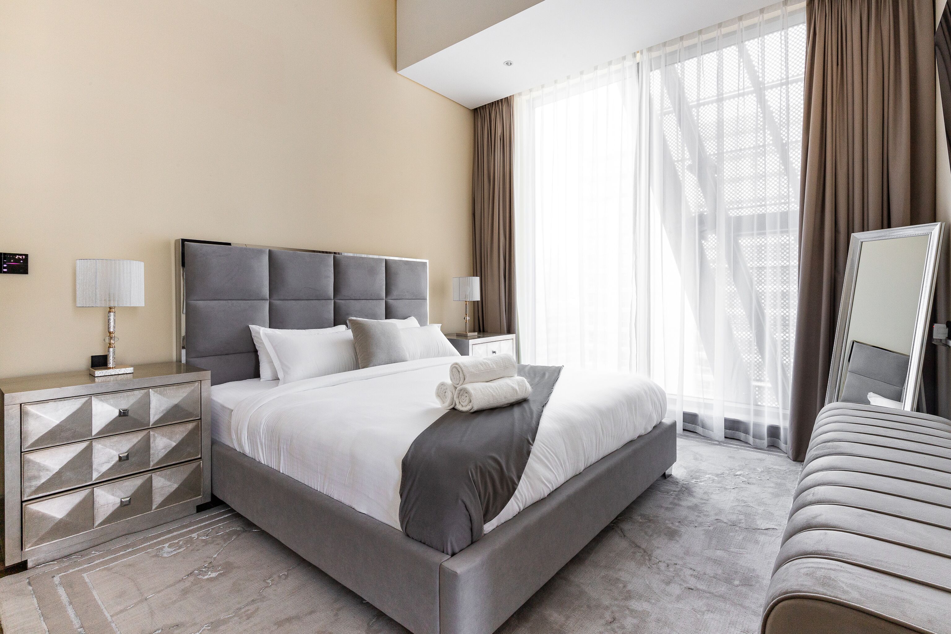 Een moderne hotelkamer met een groot bed, een nachtkastje en een raam met gordijnen.