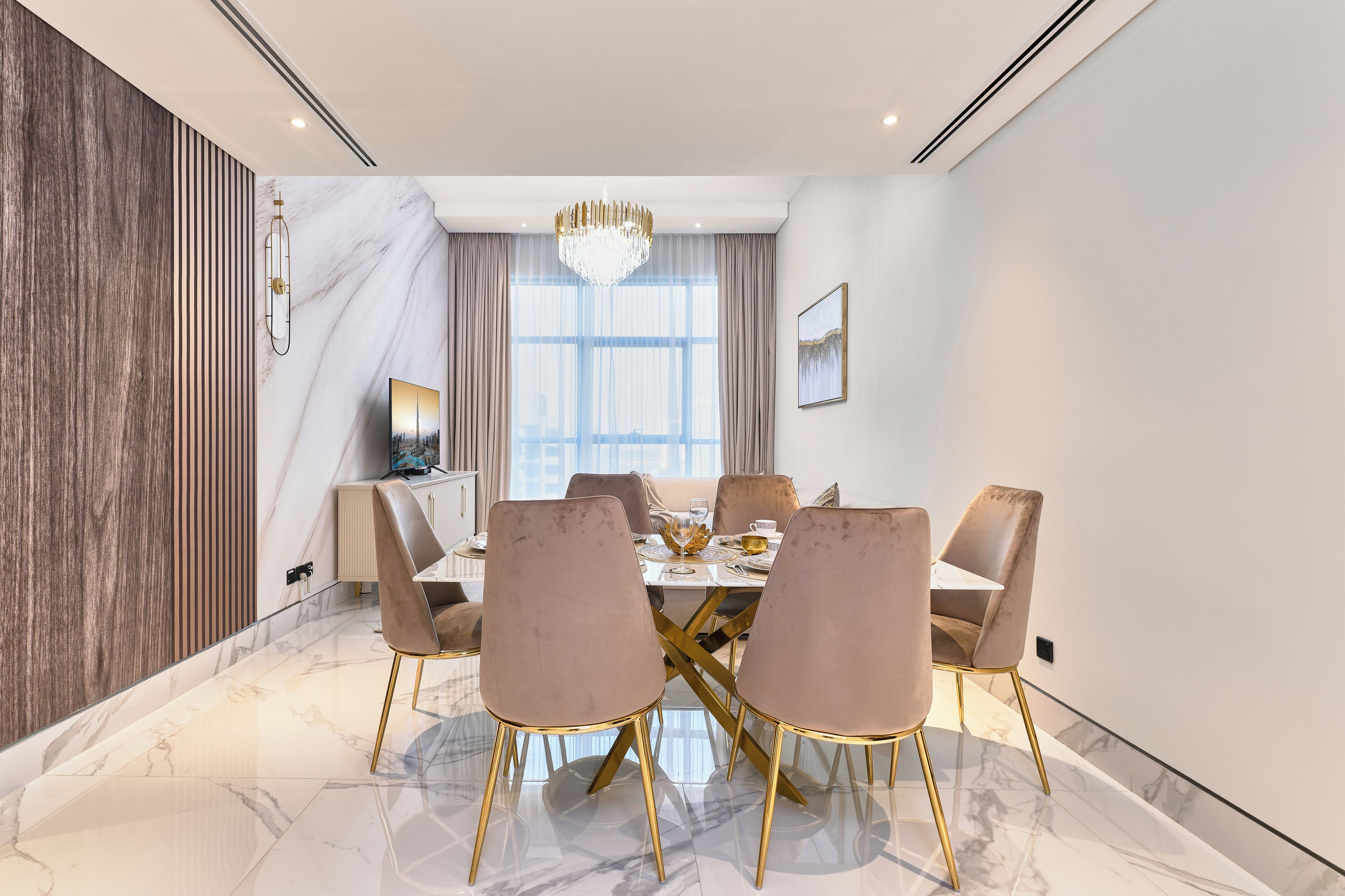 A dining room with a marble floor, a chandelier, and a large window with curtains.