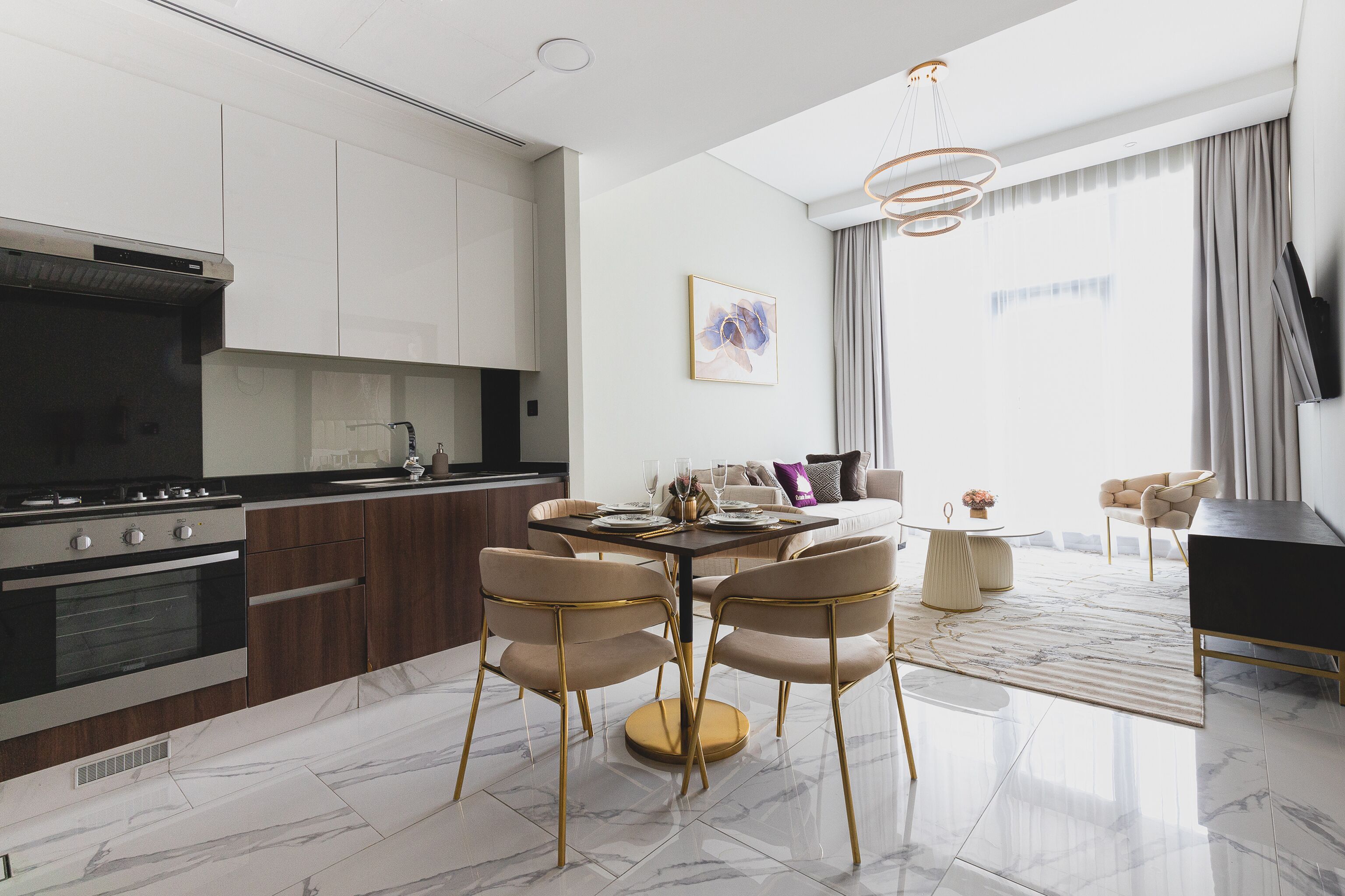 A modern kitchen with dark cabinetry, a central island, and a dining area with a marble floor.