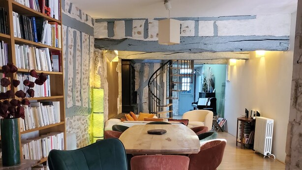 Una sala de estar acogedora con suelo de madera, una mesa redonda y una estantería llena de libros.