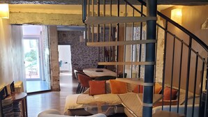 Un amplio salón con un sofá moderno, un sillón redondo y una escalera.