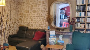 Una sala de estar con pared de piedra, sofá de cuero, mesa de centro de madera, sillón color turquesa y estantería.