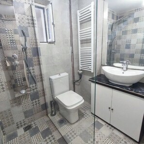 A bathroom with patterned tiles, a toilet, a sink, and a shower.