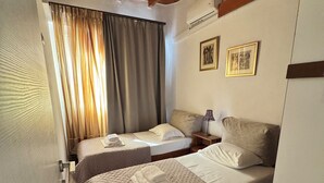 A hotel room with two beds, wooden ceiling beams, a window with curtains, and a wall-mounted air conditioner. - Classic 3-bedrooms apartment with swimming pool in Meronas (Meronas)