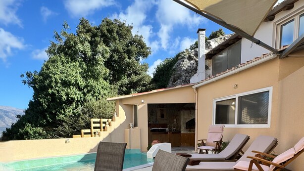 A poolside area with lounge chairs and a table, a covered patio, and a view of a mountain and trees. - Classic 3-bedrooms apartment with swimming pool in Meronas (Meronas)