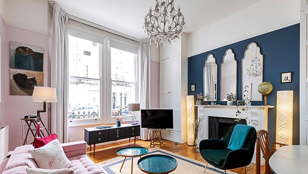 A living room with a sofa, two side tables, a TV, a fireplace, and a dining area. - Lovely One-bedroom Flat Near West Kensington (London)