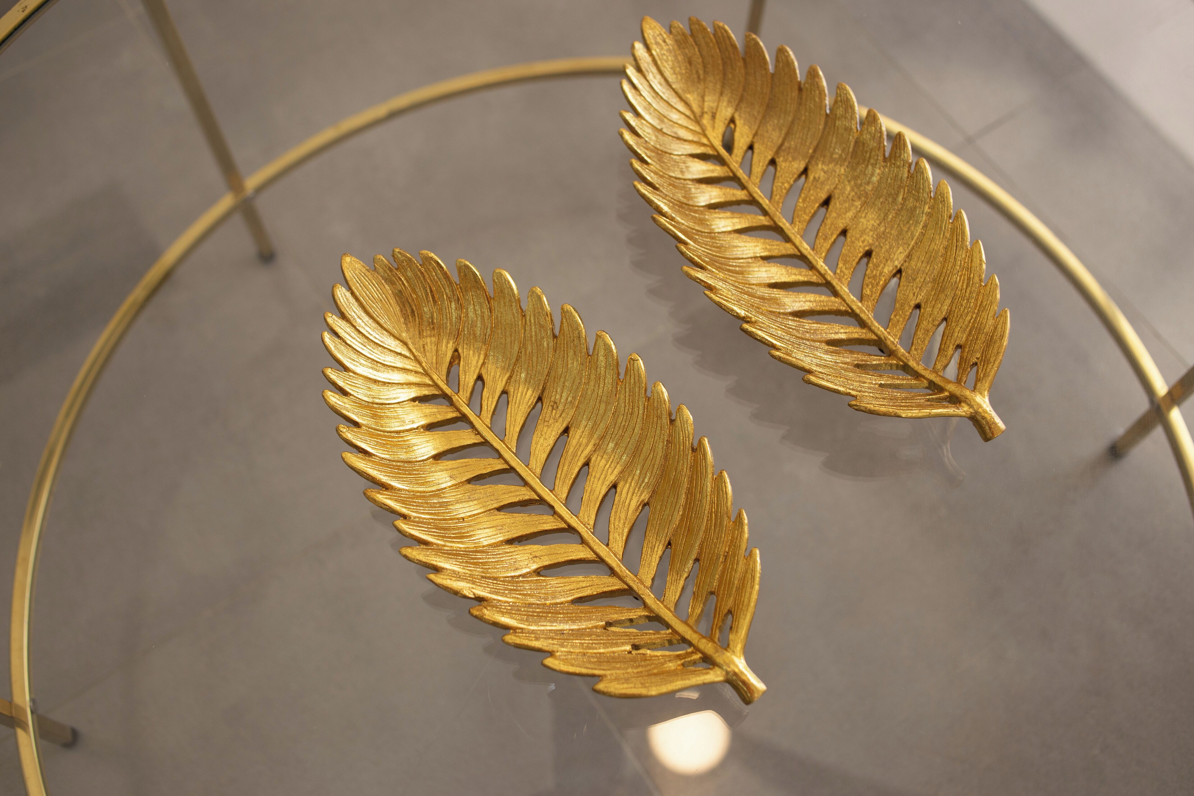 Two golden leaves on a reflective surface.