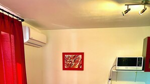 Una habitación compacta con una mesa de comedor para dos, microondas y una pequeña zona de cocina.