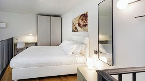 Ett modernt sovrum med en stor säng, sänglampor, en spegel och en tavla på väggen.