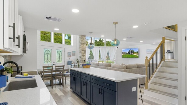A modern kitchen with a central island, built-in cabinets, and a dining area with a table and chairs. - Private Coastal home w. gaming loft, pool table, hot tub, arcades - pet friendly (Hudson)