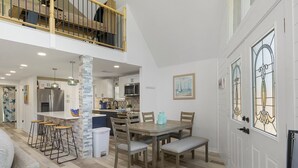 A spacious kitchen with a dining area, a staircase to an upper level, and a decorative door with stained glass. - Private Coastal home w. gaming loft, pool table, hot tub, arcades - pet friendly (Hudson)