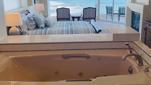 A bedroom with a large bathtub, a bed with striped bedding, two chairs, a table, and a view of the ocean. - Amazing OCEANFRONT Views! 2HUGE Rosarito Condos/Entire Floor! Priv Beach SurfK38 (Playas de Rosarito)