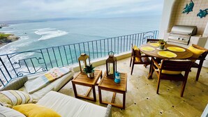 A balcony with a view of the sea, a dining table with yellow placemats, and a grill. - Amazing OCEANFRONT Views! 2HUGE Rosarito Condos/Entire Floor! Priv Beach SurfK38 (Playas de Rosarito)