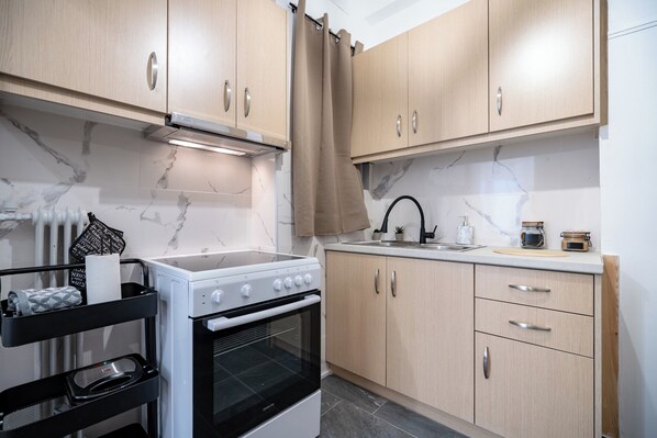 A modern kitchen with light wood cabinets, a white stove, and a black oven.