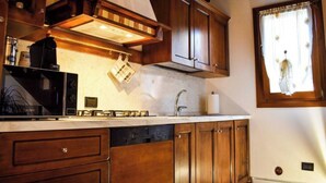A kitchen with wooden cabinets, a built-in microwave, and a window with curtains. - Il Vicoletto Marostica - ITALY (Marostica)