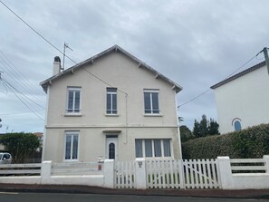 A two-story house with a white facade, a front door, and a small porch.