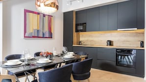 Une cuisine moderne avec des meubles de couleur sombre, un plan de travail en bois et un four encastré.