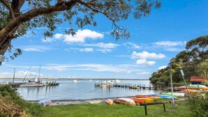 A marina with boats docked, a grassy area, and a tree in the foreground.