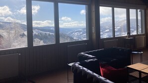 Una habitación con ventanas amplias que ofrecen vistas a montañas nevadas.