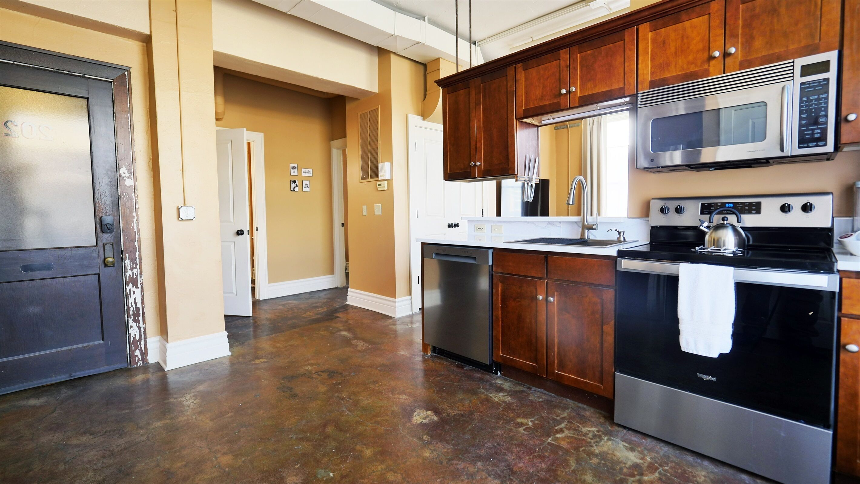 A kitchen with stainless steel appliances, wooden cabinets, and a tiled floor.