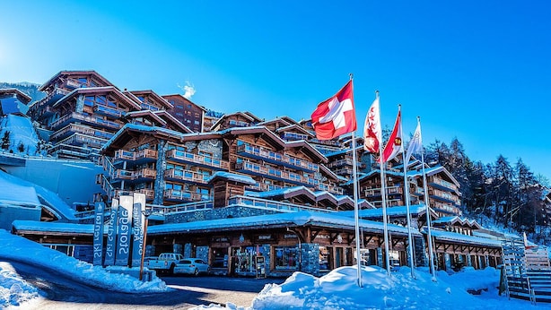 Un rifugio in legno a più piani con balconi, scuola di sci e centro benessere.