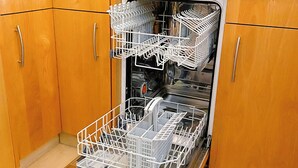 Lavastoviglie aperta con scomparti multipli e una macchina per il caffè sopra.
