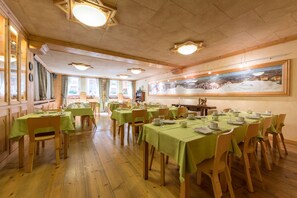 A dining area with multiple tables and chairs, wooden floors, and a large painting on the wall. - Hotel Bouton d'Or - Courmayeur (Courmayeur)