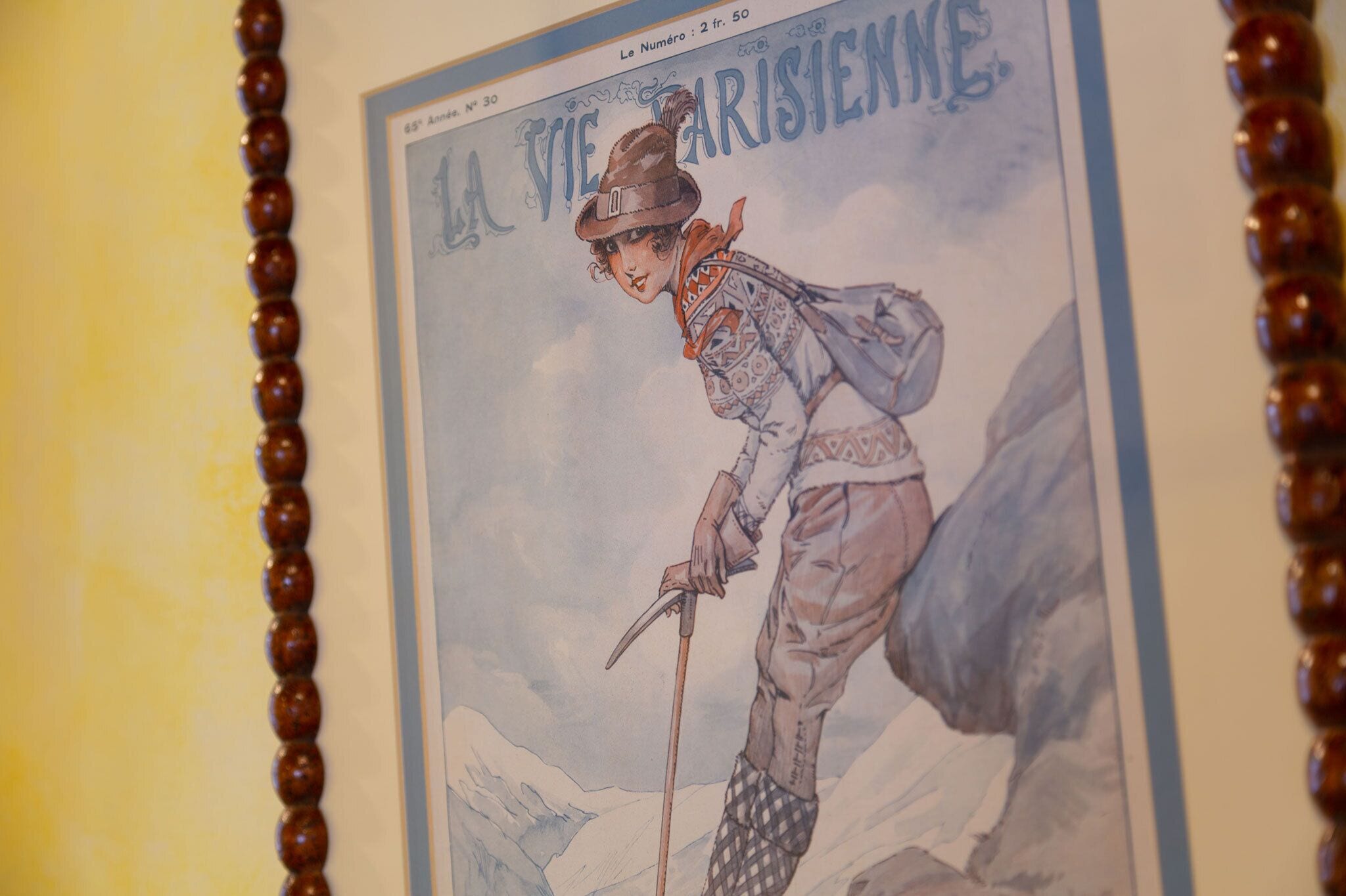 Póster antiguo con una figura de sombrero y un pico, rodeada de montañas.