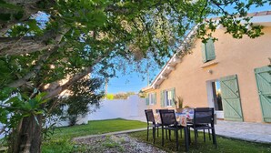 Un bâtiment doté d’un patio dallé, d’un espace extérieur aménagé avec des sièges et d’un portail vert.