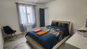 Une chambre à coucher avec un lit, une chaise, une fenêtre avec des rideaux, une porte et une petite table sur laquelle se trouve un vase.